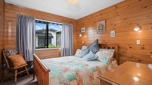 Schlafzimmer mit einem Bett, einem Tisch und einem Fenster in der Unterkunft Roseville - Snells Beach Holiday Home in Snells Beach