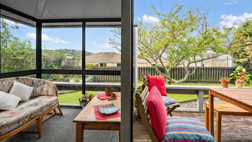 a screened in porch with a table and chairs at Beachglen - Snells Beach Holiday Home in Snells Beach