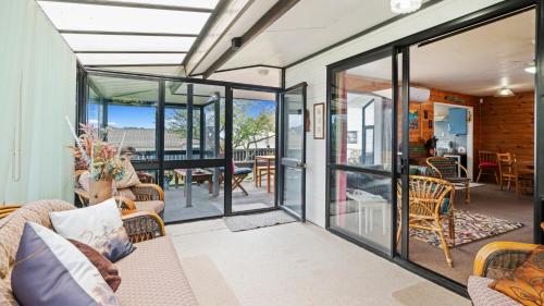a living room with glass doors and a dining room at Beachglen - Snells Beach Holiday Home in Snells Beach