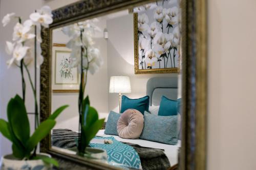 a mirror reflecting a bedroom with a bed with blue pillows at Vredenburg Manor House in Somerset West