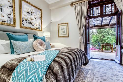 a bedroom with a bed and a door to a patio at Vredenburg Manor House in Somerset West