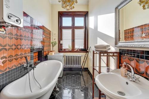a bathroom with a tub and a sink and a mirror at Danzig 1925 Old Town Apartment in Gdańsk