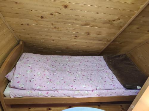 a small bed in a wooden room in a roof at Vila Carobna suma Tara in Bajina Bašta