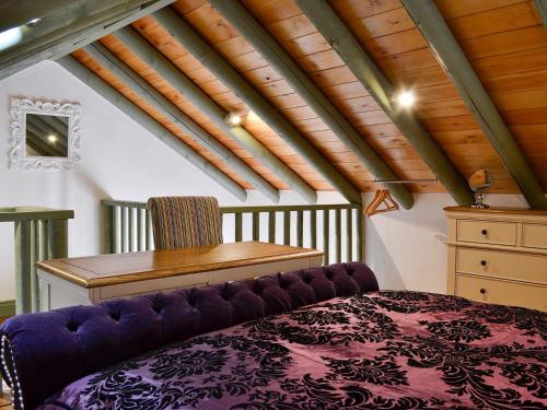 a attic room with a purple bed and a desk at Darcis Lodge - Uk1297 in Threlkeld