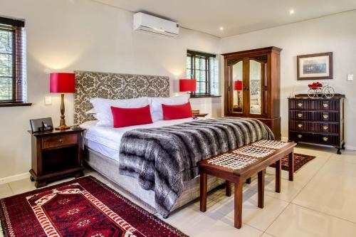 a bedroom with a large bed with red pillows at Vredenburg Manor House in Somerset West