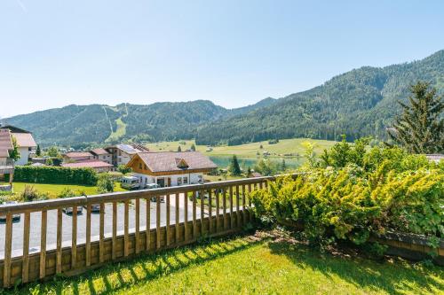 a house with a fence and mountains in the background at Ferienhaus Holzer in Weissensee