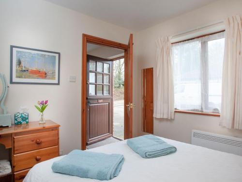 um quarto com uma cama, uma cómoda e uma janela em The Stables em Clyst Saint Mary