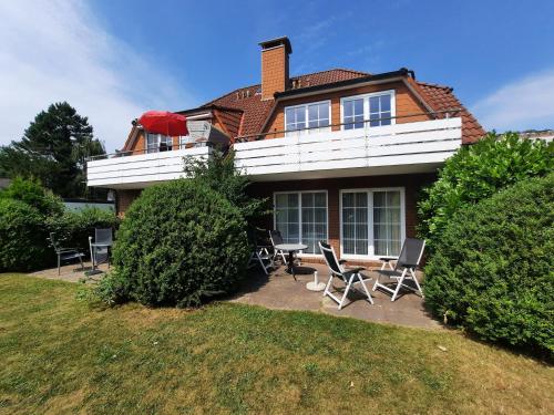 una casa con sillas y una mesa frente a ella en Residenz Vogelsand 1, en Cuxhaven