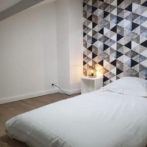 ein Schlafzimmer mit einem weißen Bett und einer gefliesten Wand in der Unterkunft L’atelier C magnifique Loft avec terrasse privée in Saint-Étienne