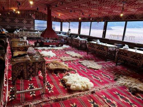 una sala da pranzo con tavoli e sedie su un tappeto rosso di Desert Bird Camp a Wadi Rum