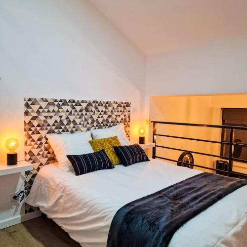 ein Schlafzimmer mit einem großen weißen Bett mit Kissen in der Unterkunft L’atelier C magnifique Loft avec terrasse privée in Saint-Étienne