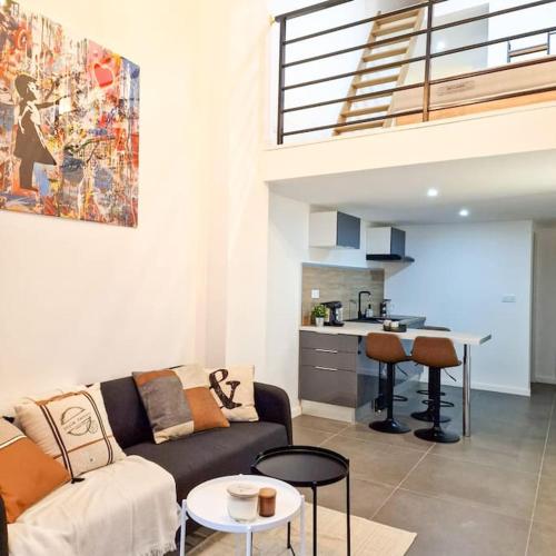 ein Wohnzimmer mit einem Sofa und einer Küche in der Unterkunft L’atelier C magnifique Loft avec terrasse privée in Saint-Étienne