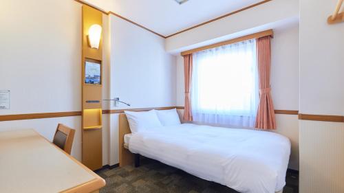 a small room with a bed and a window at Toyoko Inn Kakegawa eki Shinkansen Minami guchi in Kakegawa