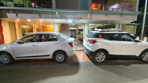 two white cars parked in front of a building at SALAS EXECUTIVE in Mahabaleshwar