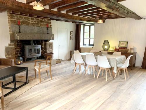 un salon avec une table et des chaises et une cheminée dans l'établissement Maison de charme à Joué-du-Bois avec vue sur le lac, à Joué-du-Bois