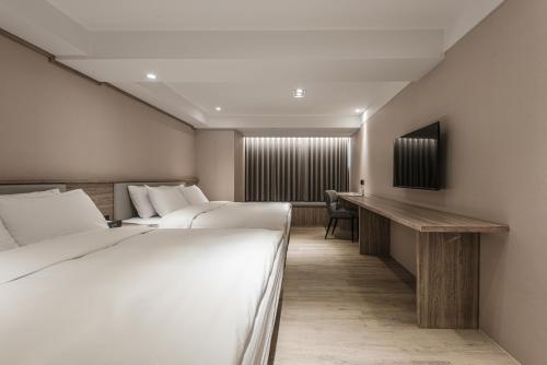 a hotel room with two beds and a desk at Spring Rhapsody Hotel in Taichung