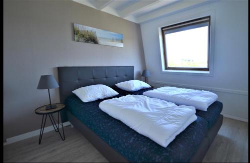 1 dormitorio con 1 cama con 2 almohadas en Kustverhuur, Park Schoneveld, Zeester 25, en Breskens