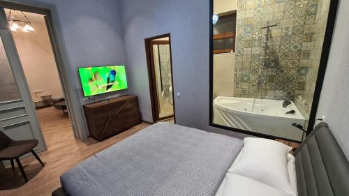 a bedroom with a bed and a tub and a tv at Nino's Cosy Apartment in Kutaisi