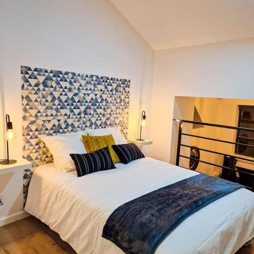 a bedroom with a large white bed with two pillows at Grand Loft avec terrasse privée in Saint-Étienne