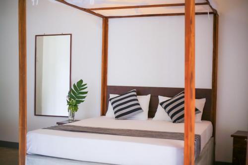 a bedroom with a four poster bed with a mirror at Emma's Sea View in Hiriketiya