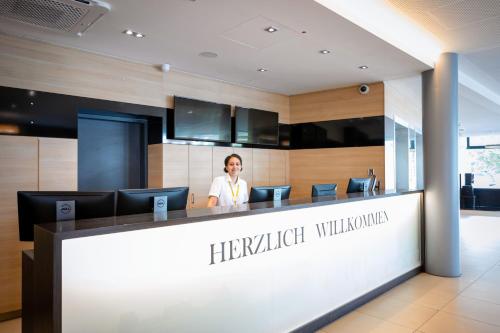 a woman is standing behind a reception desk in a hotel lobby at Staycity Aparthotels Heidelberg in Heidelberg