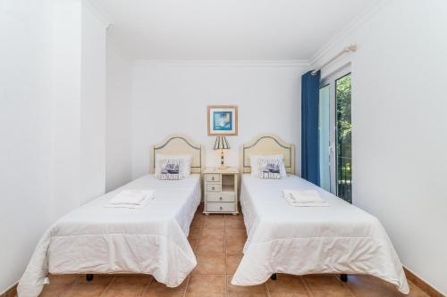 two beds in a white room with a window at Jardins Meia Praia 104 by Algarve Golden Properties in Lagos
