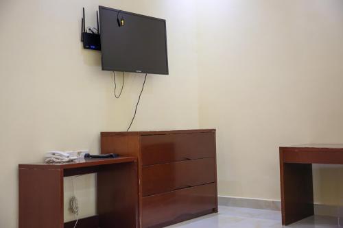 a room with a tv on the wall and a dresser at Park Complex in Salalah