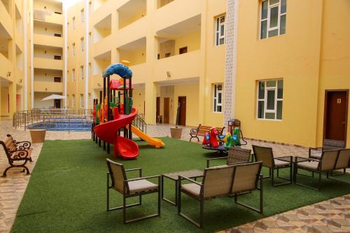 a playground in a building with chairs and a slide at Park Complex in Salalah