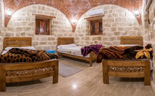 Habitación con 3 camas en una habitación de piedra. en Zad El Mosafer Guest House, en Tunis