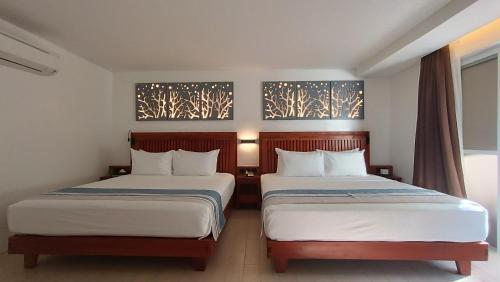 a hotel room with two beds and two paintings on the wall at Aira Boracay Hotel in Boracay