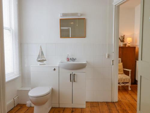 a white bathroom with a toilet and a sink at Shipwrights Cottage in Teignmouth