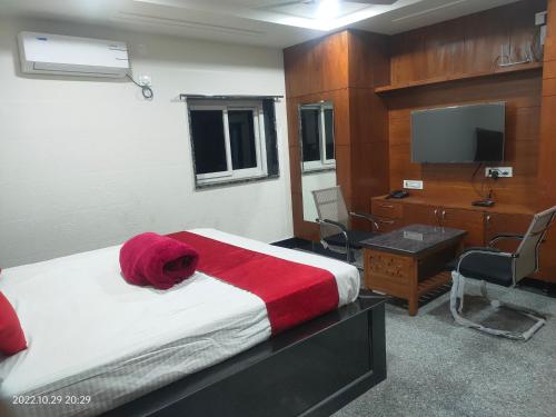 um quarto com uma cama com um cobertor vermelho e uma secretária em Hotel New Maruthi Inn, LB Nagar em Hyderabad