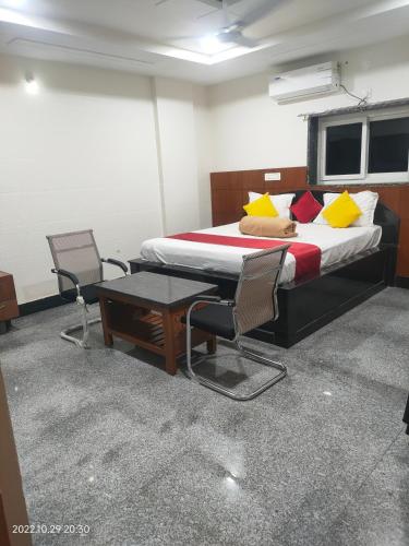 a bedroom with a bed and two chairs and a table at Hotel New Maruthi Inn, LB Nagar in Hyderabad