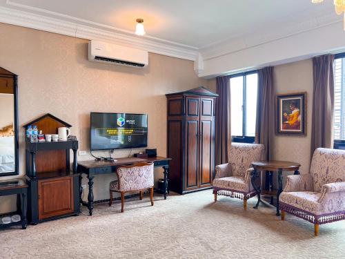 a living room with a television and a desk and chairs at No. 6 Baowanglai Hotel in Caotun