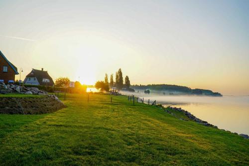 a house on a hill next to a body of water at Haus Besch - Apartment "Kleine Kapitänskajüte" in Alt Reddevitz