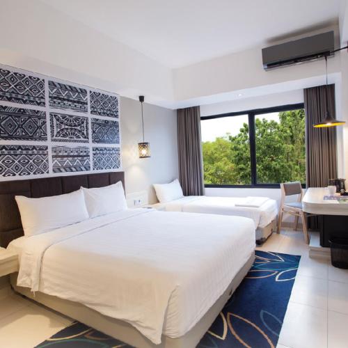 a hotel room with two beds and a desk at Aston Anyer Beach Hotel in Anyer