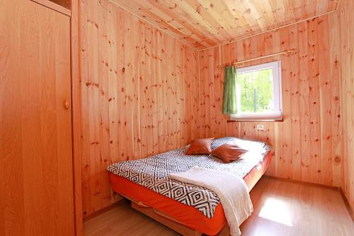 a bedroom with a bed in a wooden cabin at Domki wczasowe Mazury - Ferienhaus Masuren - do 12 osób - idealny dla grup in Dłużek
