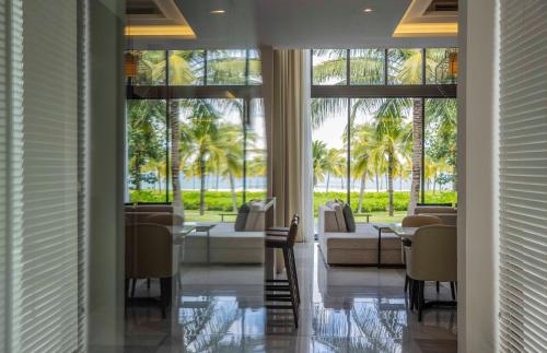 a lobby with chairs and a couch and palm trees at Vinpearl Resort & Golf Nam Hoi An in Hoi An