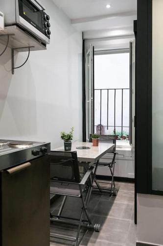 une cuisine avec une table et un four micro-ondes ainsi qu'une fenêtre dans l'établissement Studio dans le 17ème, à 2km de Sacré Cœur, à Paris