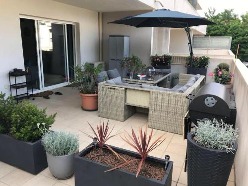 une terrasse avec des plantes, un parasol et un grill dans l'établissement T2 chaleureux avec grande terrasse vue mer, à Bastia