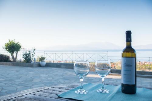 a bottle of wine and two wine glasses on a table at Onar Zin Seabliss - Majestic Getaways in Xylokastro