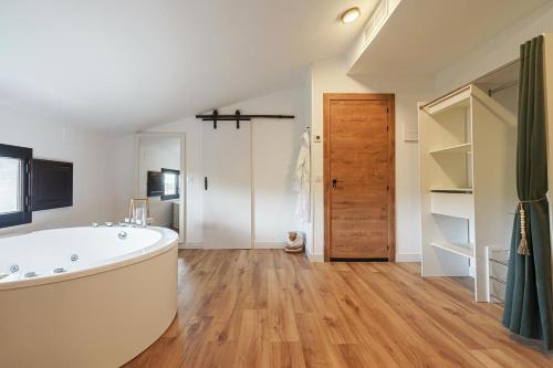 een grote badkamer met een groot bad en houten vloeren bij DUO SOMNIA, suites con jacuzzi y chimenea, only adults 
