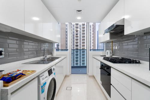 a white kitchen with a sink and a dishwasher at GlobalStay Business Bay Waves Tower Apartments Dubai in Dubai