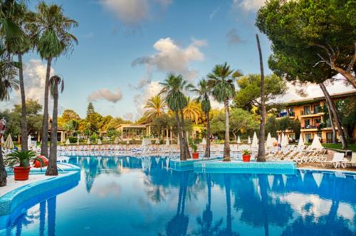 a large swimming pool with palm trees and chairs at Caprice Vell Mari Hotel & Resort - New Opening 2026 in Can Picafort