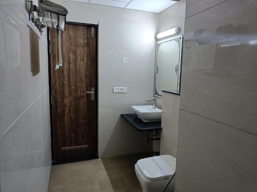 a bathroom with a toilet and a sink and a door at The Dwelling Paradise in Greater Noida