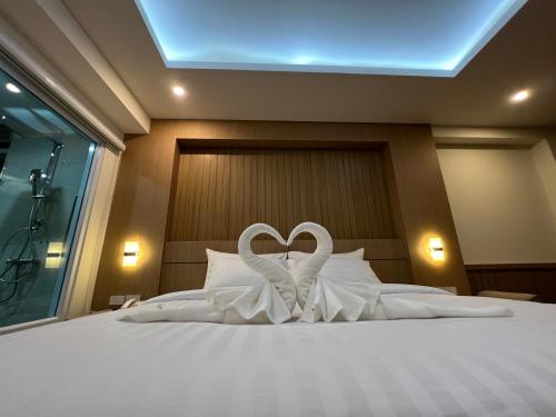 1 cama con 2 toallas blancas en forma de corazón en เดอะสแควร์โฮเทลนครพนม, en Nakhon Phanom