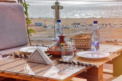 a table with plates and bottles on it with a view of the beach at BLUE WAVE LODGE in Imi Ouaddar