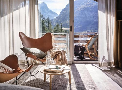 a living room with chairs and a table and a large window at CERVO Mountain Resort in Zermatt