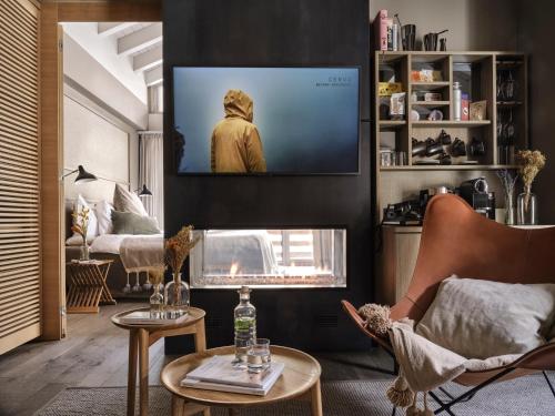a living room with a tv above a fireplace at CERVO Mountain Resort in Zermatt