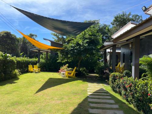 a garden with a house with a large hammock at Hanoii House in Ko Mak